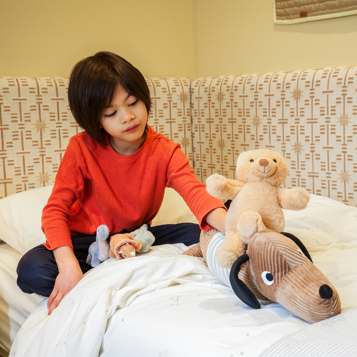 Lionel playing with teddies on bed 1140x1140px