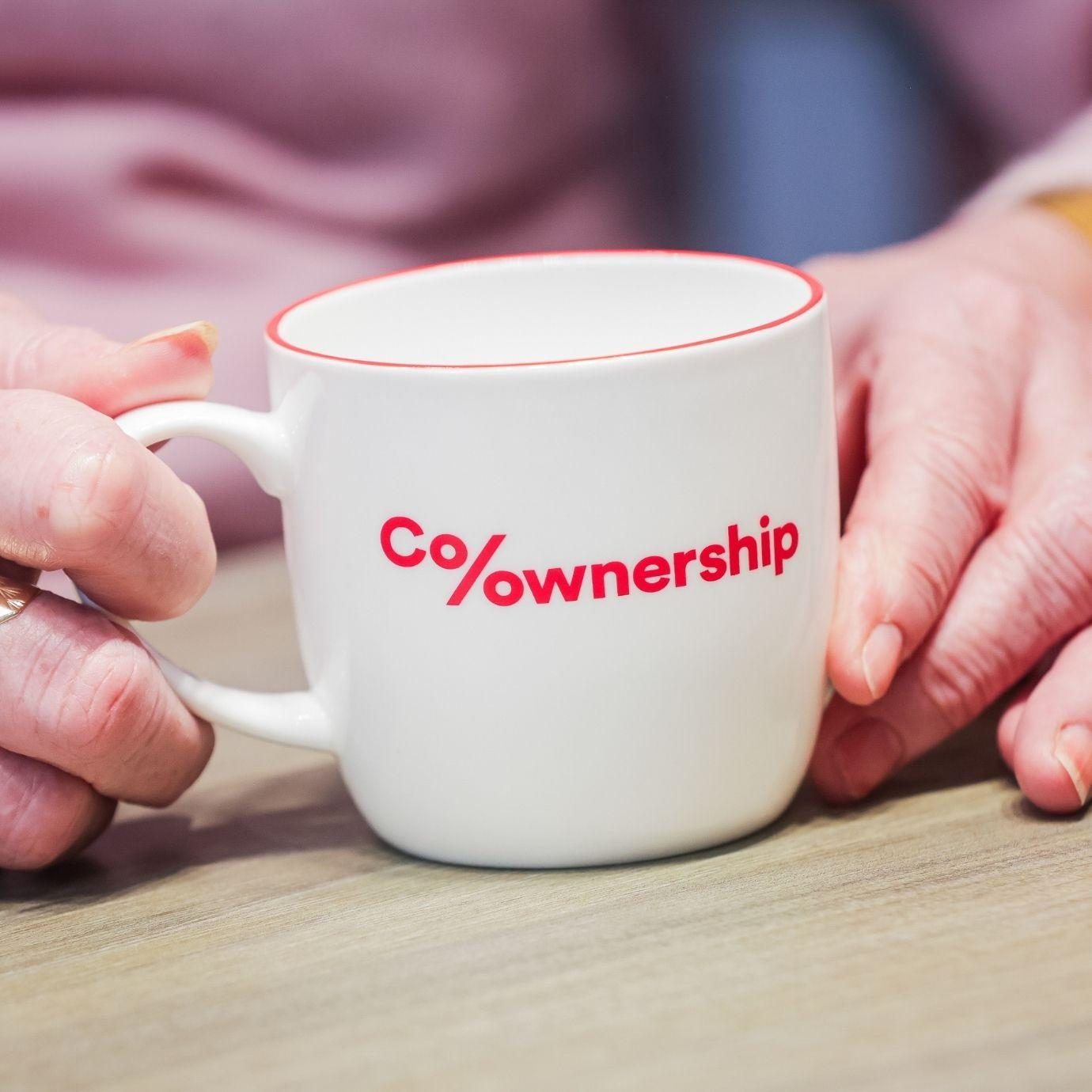 Close up of a person holding a branded mug on table