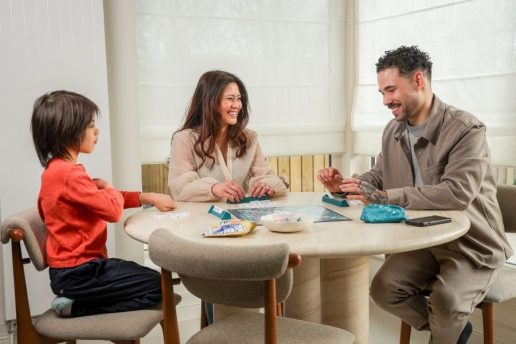 Woman, man and child playing scrabble at kitchen table