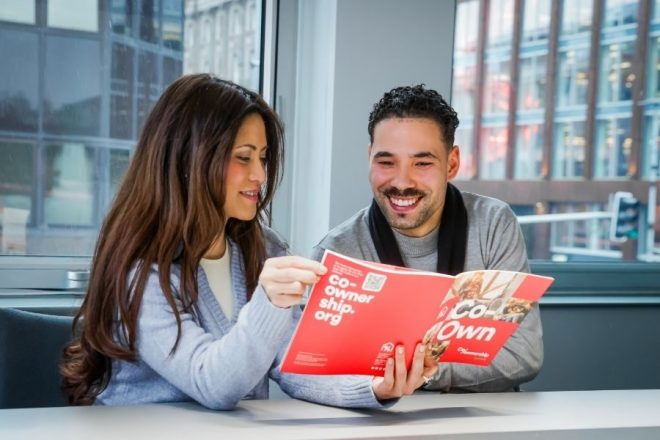 Man and woman in meeting room looking and smiling at brochure