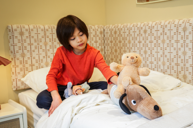 Lionel playing with teddies on bed 900x600px