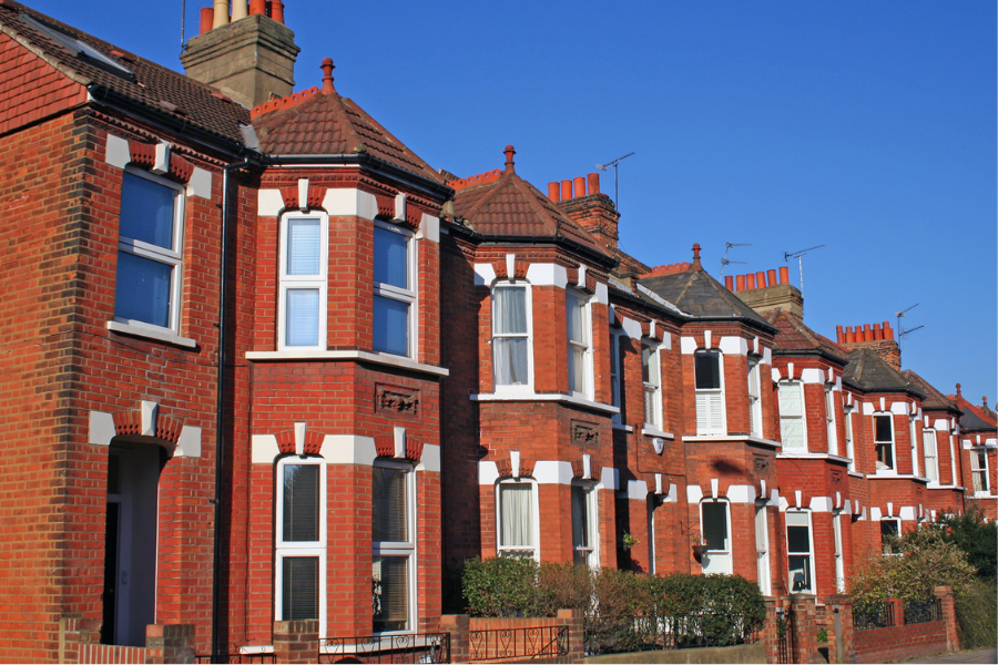 A row of red brick terrace houses against a blue sky
